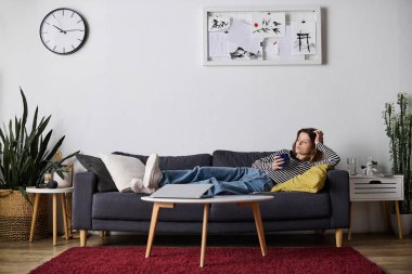 Etrafı rahat bir daireyle çevrili, kahvesini yudumlayan genç bir kadın..