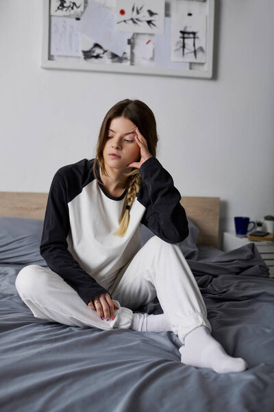 A young woman relaxes in her cozy bedroom, feeling the weight of the day as she spends time in bed.
