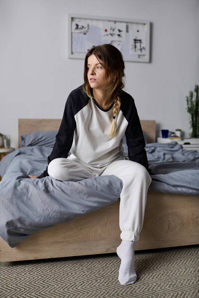 A young woman spends a leisurely day in bed, embracing comfort in her stylish apartment.