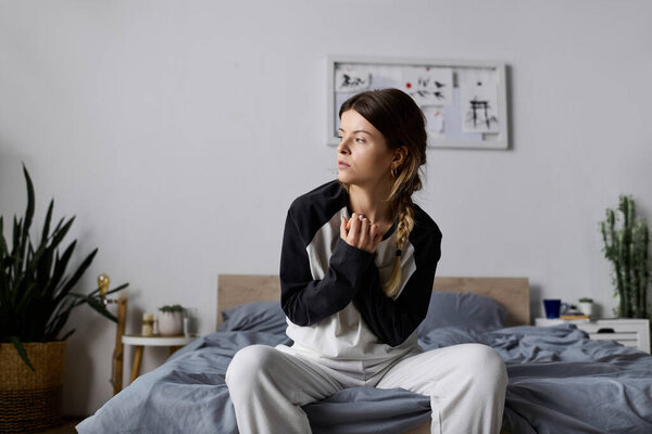 A young woman enjoys a quiet day in bed, relaxing in her cozy bedroom and focusing on self-care.