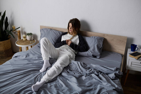 A young woman relaxes in her cozy apartment, enjoying a day of self-care in bed.