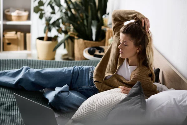 Genç bir kadın, modern dairesinde tembel bir günün tadını çıkarırken yatakta dinleniyor..