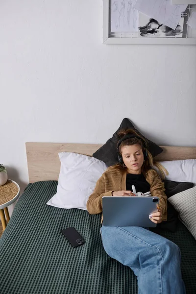 Genç bir kadın, modern bir apartman dairesinde cihazına odaklanarak gününün tadını çıkarıyor..