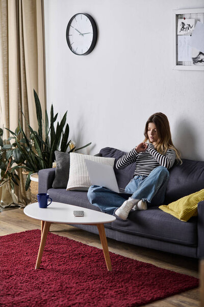 A young woman spends her day lounging on sofa, enjoying comfort and solitude in her modern space.