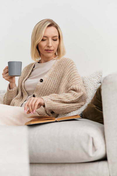 В спокойной квартире блондинка расслабляется с книгой и теплым напитком в уютном одеянии.