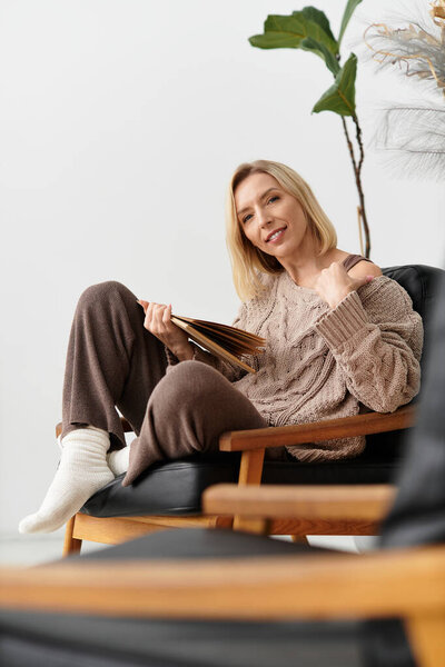Blonde woman enjoys a quiet moment in her modern apartment, wrapped in comfort on a winter day.