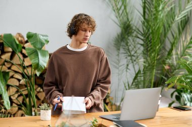 Genç ve yaratıcı bir adam yeşilliklerle dolu şık bir çalışma alanında işine odaklanıyor..