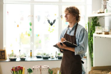 Bitkilerle dolu parlak bir alanda, genç bir adam yaratıcı fikirlerini neşeli bir şekilde dile getirir..