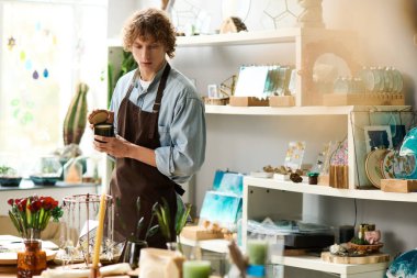 Genç adam sanatsal çalışmalarına materyallerle dolu renkli ve ilham verici bir atölyede odaklanıyor..