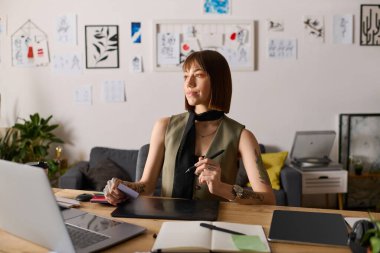 Genç bir kadın, ilham verici sanat eserleriyle çevrili olan stüdyosunda yaratıcı işler yapıyor..