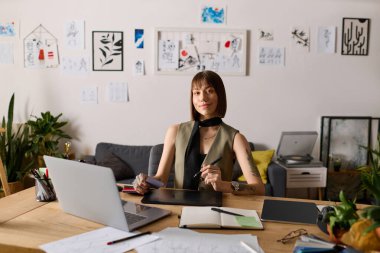 Evdeki genç kadın, ilham verici çizimler ve yeşilliklerle çevrili dijital sanat eserleriyle uğraşıyor..