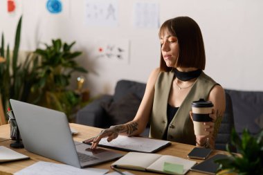 Genç bir kadın evdeki masasında oturuyor, bir fincan kahve içerken işine dalmış..