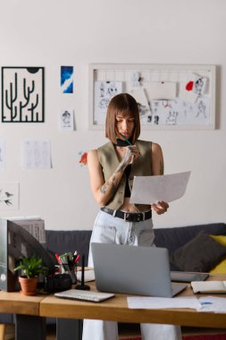 Genç bir kadın, çizimler ve tasarım araçlarıyla çevrili, ev stüdyosunda yaratıcı işler yapıyor..