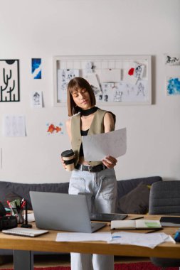 Genç bir kadın, elinde kahve tutarken sanat eserlerini gözden geçirir..