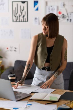 Sanatsal materyallerle çevrili genç bir kadın, çalışma alanında yaratıcı işler yapıyor..