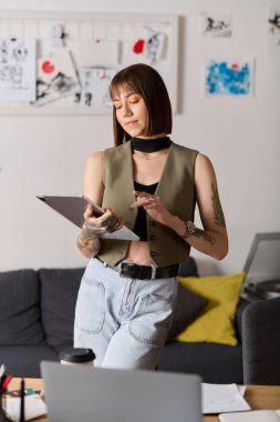 Genç bir kadın sanat ve aletlerle çevrili yaratıcı ev ortamında düşünceli bir şekilde duruyor..