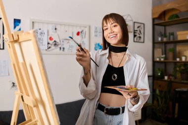 Genç kadın evde resim yaparken yaratıcılığını gösteriyor, neşe ve tutku sergiliyor..