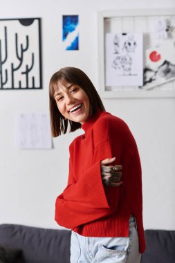 Rahat bir ev ortamındaki neşeli genç kadın sanatla dolu yaratıcı alanının tadını çıkarıyor..