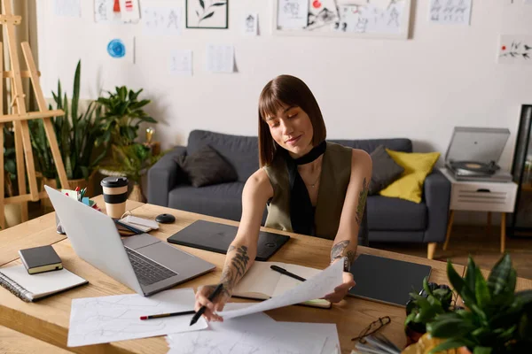 Genç bir kadın sanat malzemeleri ve yeşilliklerle çevrili, kendi masasında yaratıcı işler yapıyor..