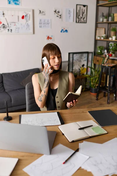 Genç bir kadın, rahat bir ofisteki not defterine not tutarken telefonla konuşuyor..