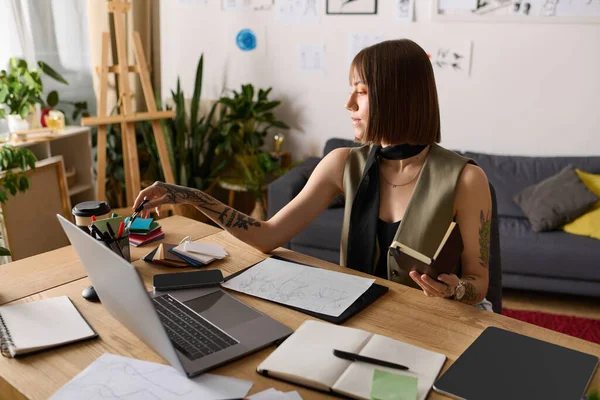 Masasında oturan genç bir kadın resim çizmeye ve sanat malzemelerini düzenlemeye odaklanmış..