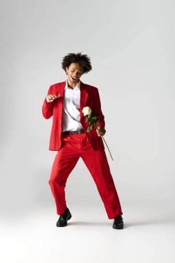 Zarif giyinmiş yakışıklı genç adam bir gül ile dans ediyor, neşe ve neşe saçıyor..