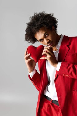 Bu genç adam, kalp taşırken çarpıcı kırmızı bir elbiseyle zarafetini sergiliyor..