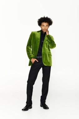 Yeşil ceketli yakışıklı bir genç, basit bir arkaplana karşı güvenle poz verir..