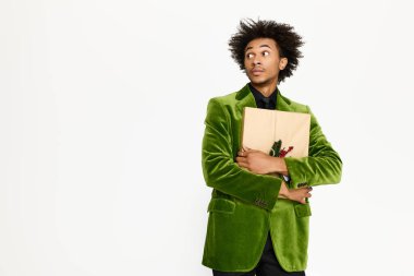 Zarif yeşil elbiseli yakışıklı genç bir adam sürpriz ve merakını ifade eden bir hediye taşıyor..