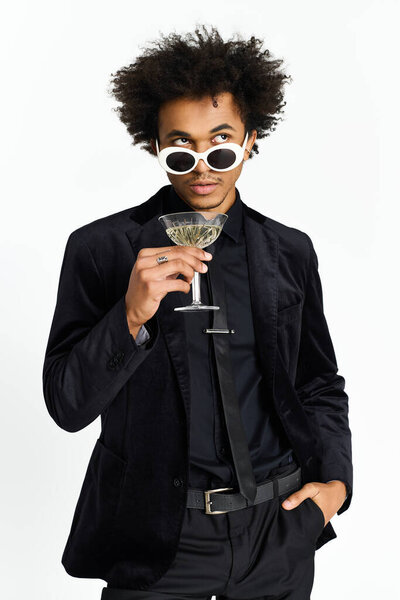 Handsome young man dressed in elegant clothes holds a cocktail glass with style.