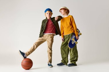 İki modaya uygun çocuk basketbolu ve kaykayı seviyor, canlı tarzlarını sergiliyorlar..