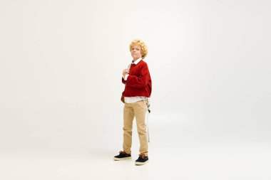 Genç bir çocuk kendine güveni tam bir şekilde şık giyinmiş, çocukluk yaratıcılığını ve modasını benimsiyor..