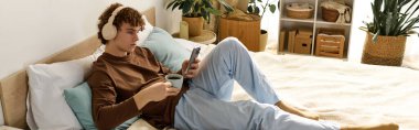 Gündelik ergen çocuk kahve içerken müzik dinliyor ve evde telefonunu kontrol ediyor.