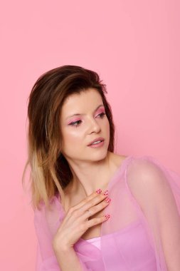 Stüdyoda poz veren genç bir kadın moda pembe makyaj malzemesi ve katıksız bir bluz giyiyor..