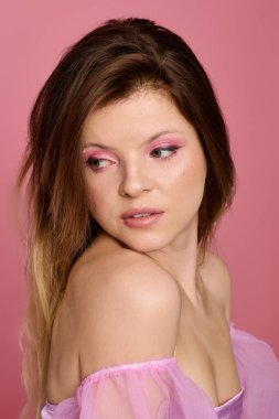 Canlı bir stüdyoda, genç ve güzel bir kadın şık pembe makyajlar ve katıksız bir bluz sergiliyor..