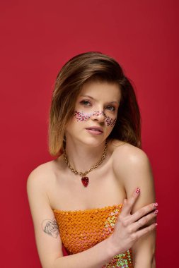 Genç bir kadın canlı bir stüdyo ortamında makyaj ve çıplak omuzlar sergiliyor.