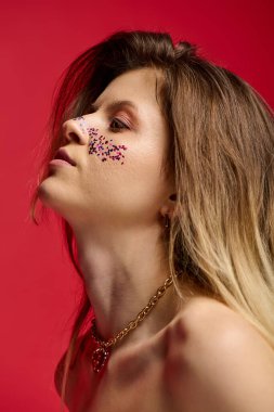 Genç bayan zarif bir şekilde poz veriyor. Parlak bir makyajla. Kalın kırmızı arka plan..