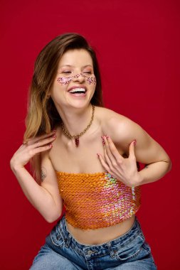 Neşeli genç bir kadın, parlak makyajını ve modaya uygun tarzını sergileyerek stüdyoda poz veriyor..