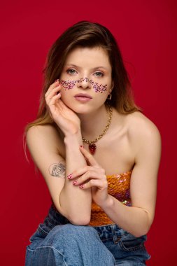 Çekici genç bir kadın kendine güvenerek poz veriyor, ışıl ışıl makyaj yapıyor ve modaya uygun giyiniyor..