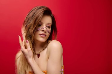 Genç bir kadın ışıl ışıl makyajını ve tarzını sergileyerek canlı bir stüdyoda zarif poz veriyor..