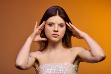 Göz makyajıyla poz veren şık genç bir kadın stüdyo ortamında güzelliğini ön plana çıkarıyor..