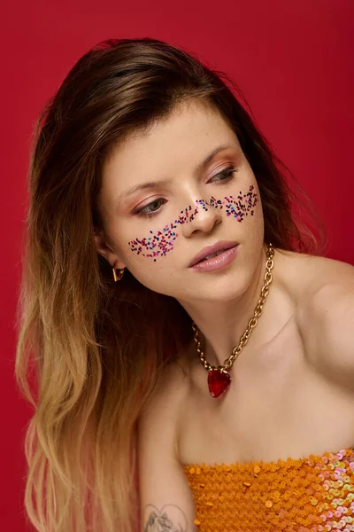 Genç bir kadın renkli bir stüdyoda ışıl ışıl makyaj ve şık kıyafetlerle zarif poz verir..