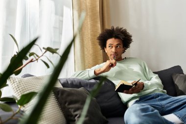 Yakışıklı genç adam rahat rahat evinde oturuyor, derin düşüncelere dalmış yazarken..