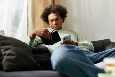 Yakışıklı genç bir adam evinde oturuyor, defterinden ve akıllı telefonundan ilham alıyor..