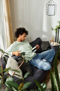 Yakışıklı, Afro-Amerikan bir adam kanepede dinleniyor, bir kitaba dalmış, evinde..