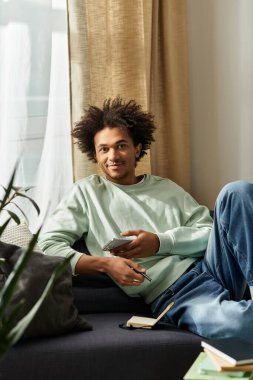 Genç bir Afrikalı Amerikalı adam şık oturma odasında rahatlıyor, sıcaklığı ve rahatlığı yayıyor..