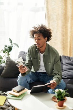 Genç adam kanepede rahatlar, rahat bir ortamda telefonunu okur ve kontrol eder..