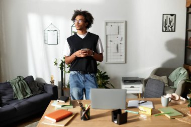 Yakışıklı bir genç adam modern oturma odasında düşünceli bir şekilde durup kahvesini yudumluyor..