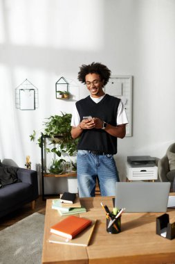 Şık, genç ve güçlü bir adam evinde rahat, akıllı telefonuna gülümsüyor..