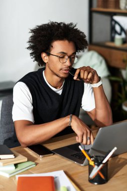 Yakışıklı genç adam laptopuna odaklanmış, rahat ve modern bir ev ortamında çalışmaya dalmış..